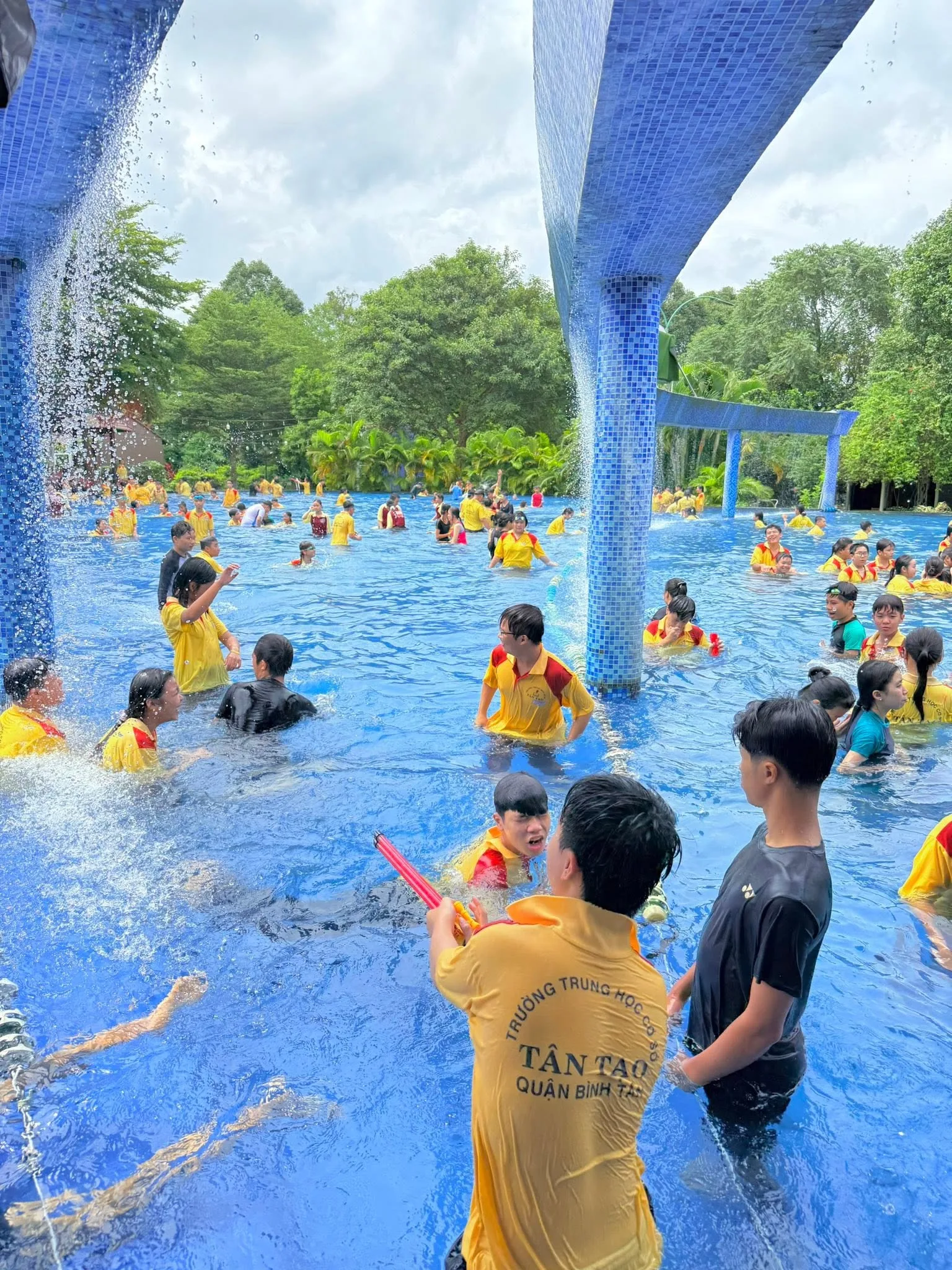 Trẻ em vui đùa dưới vòi phun nước ở hồ bơi